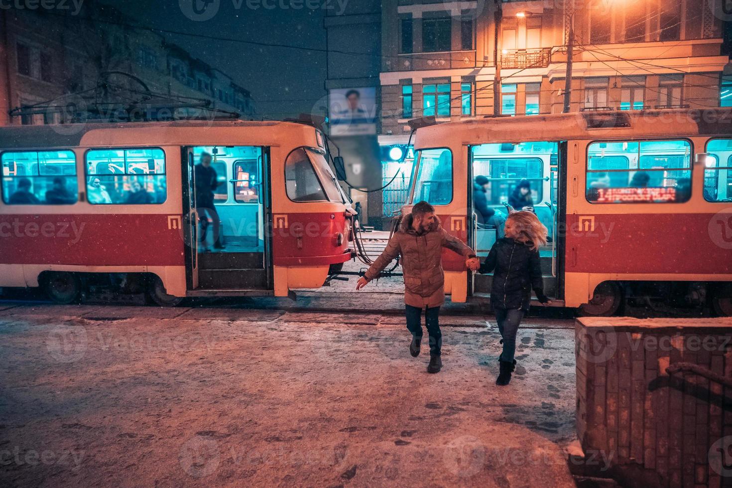 junges erwachsenes paar auf schneebedeckter straßenbahnstation foto