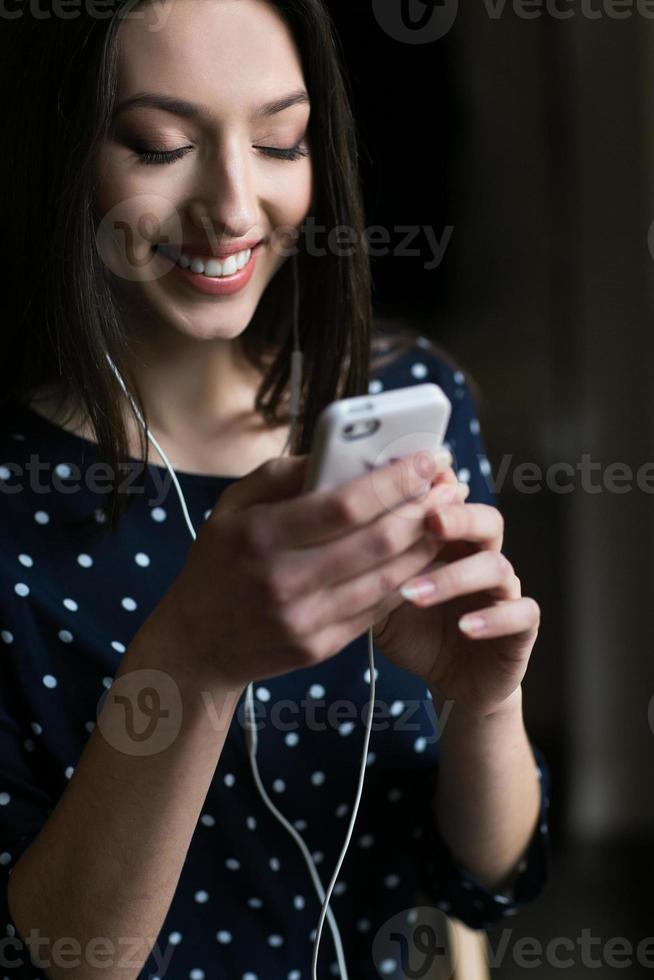 schönes Mädchen, das Musik am Telefon mit Kopfhörern hört foto