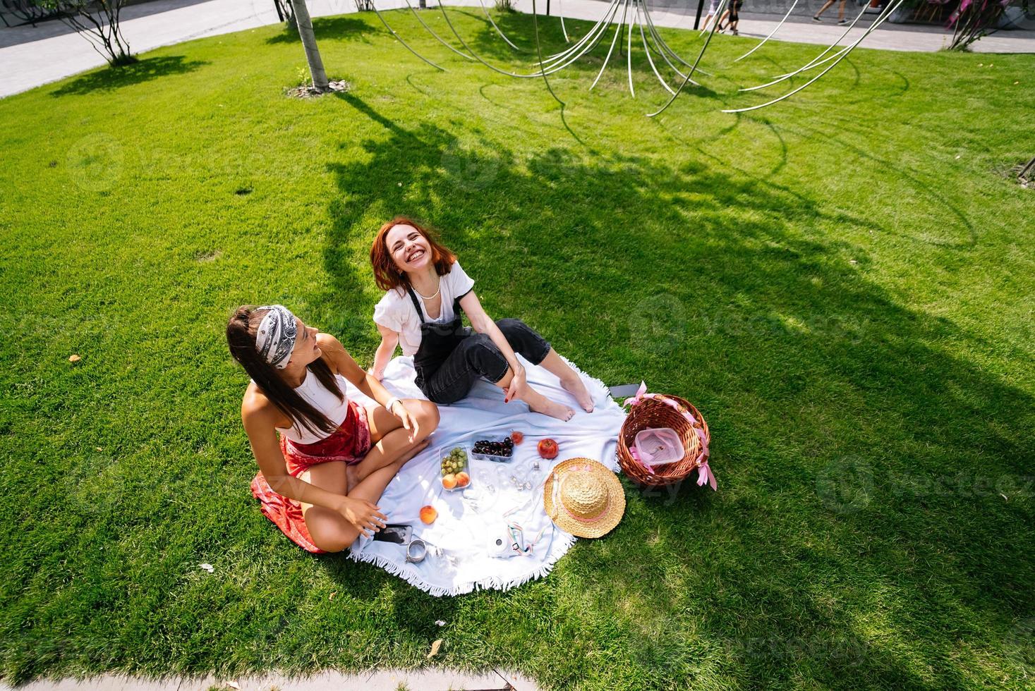 zwei frauen, die zusammen picknicken, sitzen auf dem plaid foto