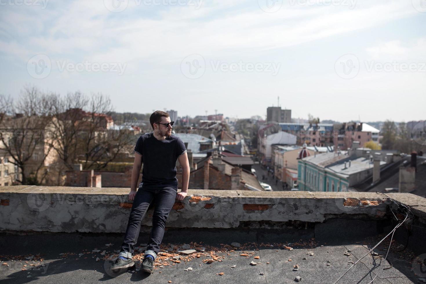 Der Mann in den authentischen Stiefeln und Jeanskanten auf dem Dach des Gebäudes in der Altstadt foto