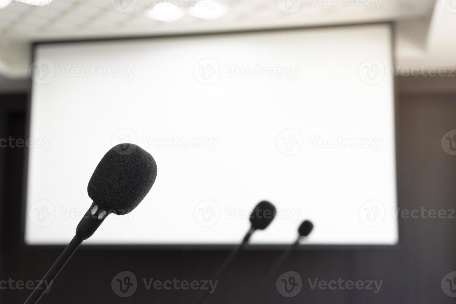 Schließen Sie das Mikrofon im Besprechungsraum mit Bildschirmprojektor-Hintergrund foto