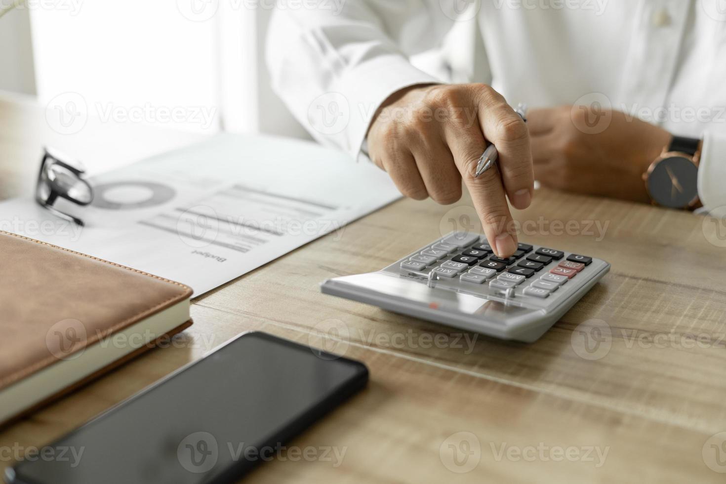 Geschäftsmann, der Unternehmensinvestitionen berechnet, Mann im weißen Hemd, der am Schreibtisch im Büro arbeitet. foto