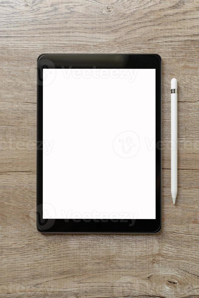 Schwarzes Tablet mit weißem, leerem Bildschirm befindet sich auf braunem Papier mit Zubehör. Ansicht von oben, flach liegend. foto