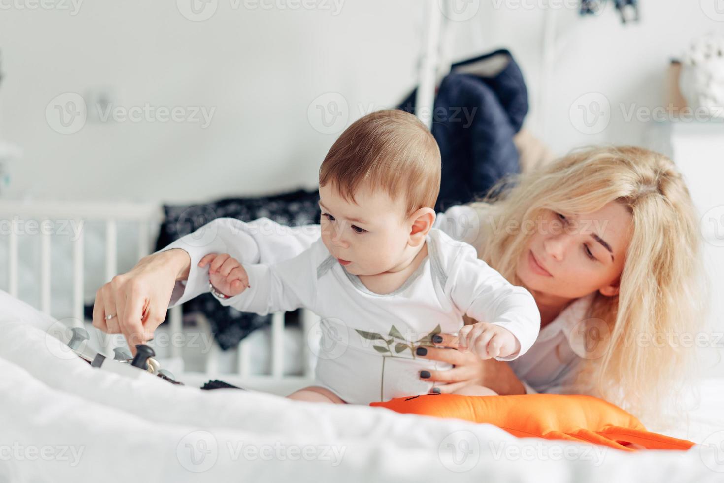 Mutter spielt mit ihrem Baby im Schlafzimmer foto