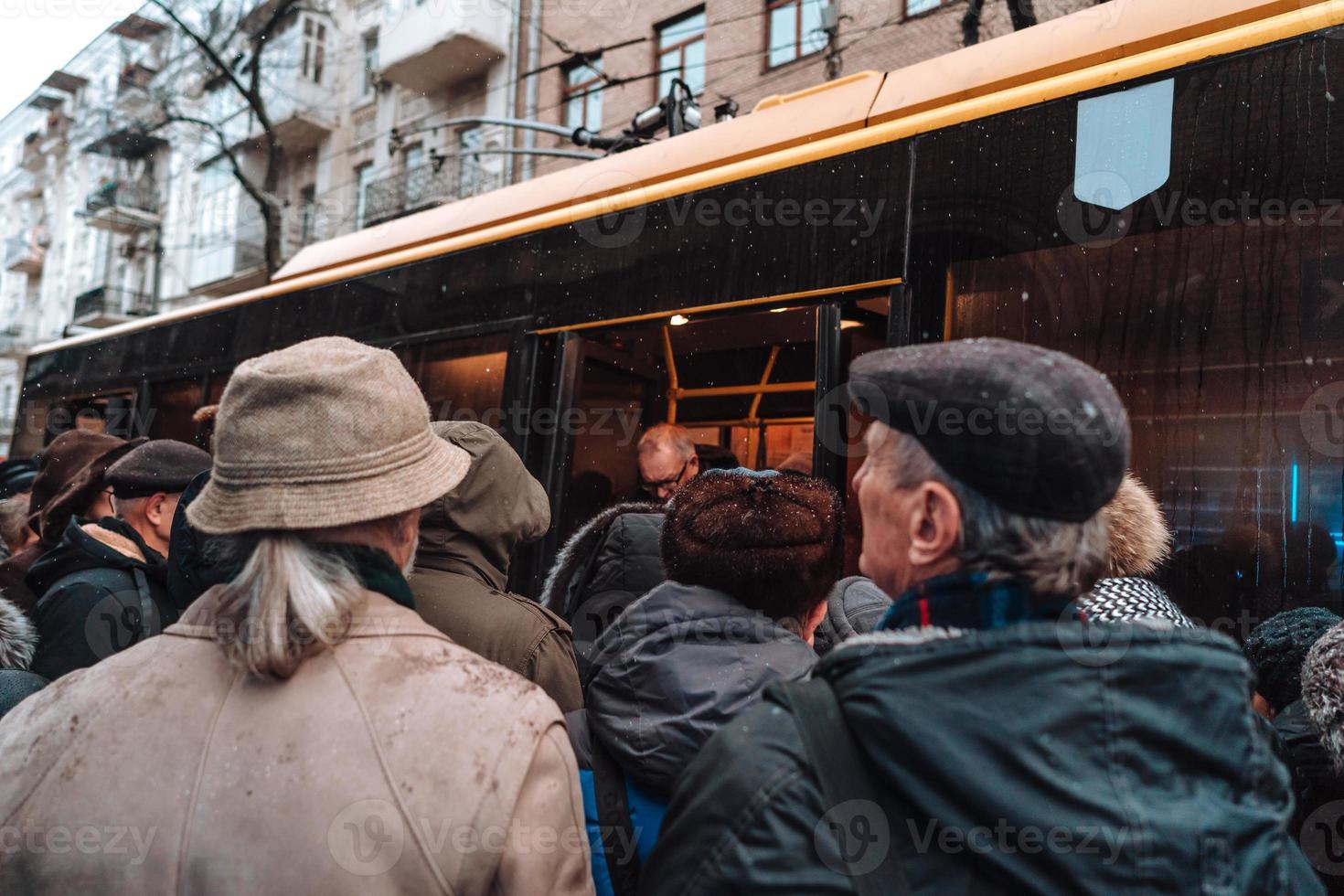 Viele nicht identifizierte Personen warten an der Bushaltestelle auf den Stadtverkehr foto