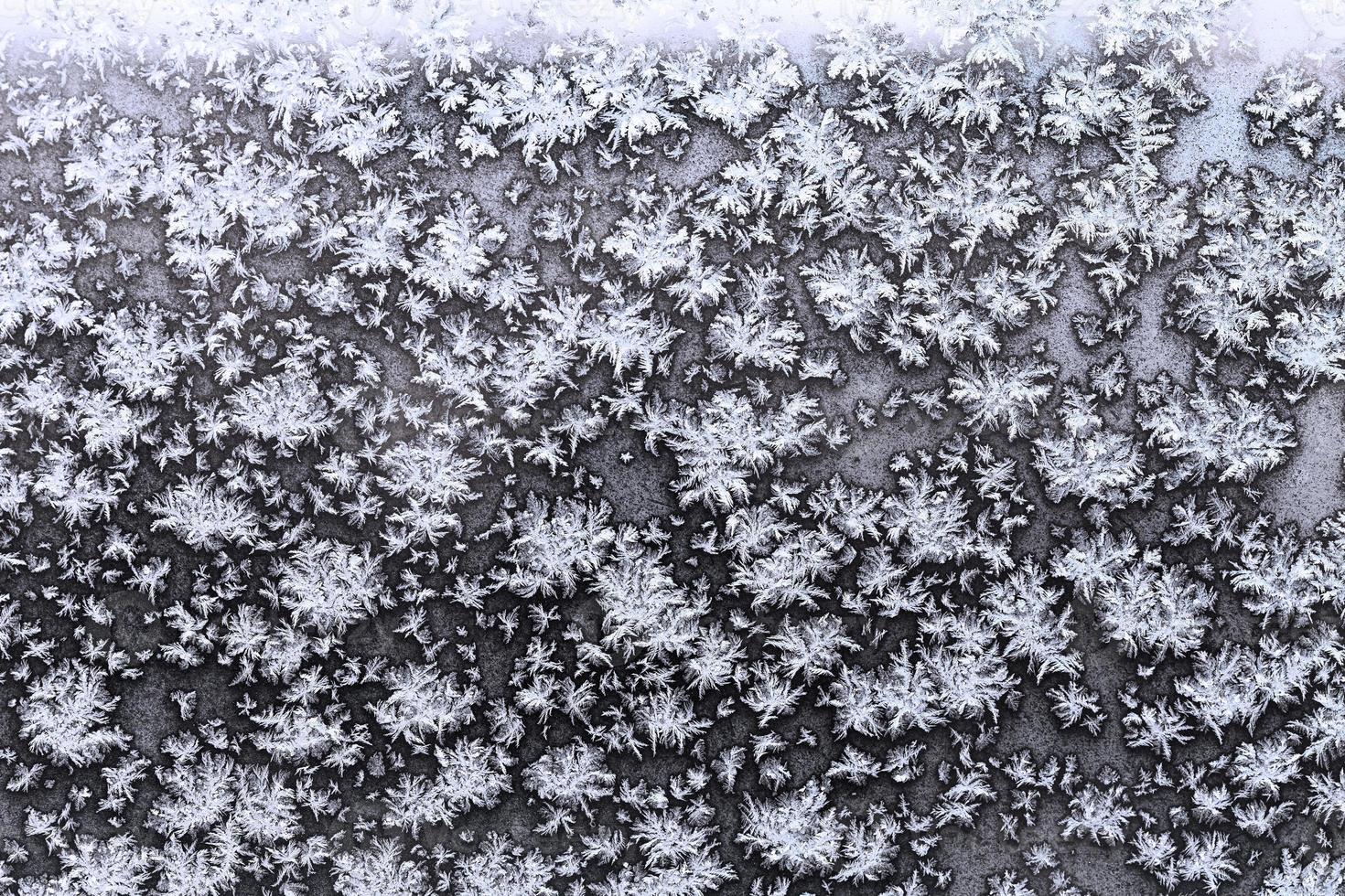 Schneeflocken und Frost auf gefrorener Fensterscheibe foto