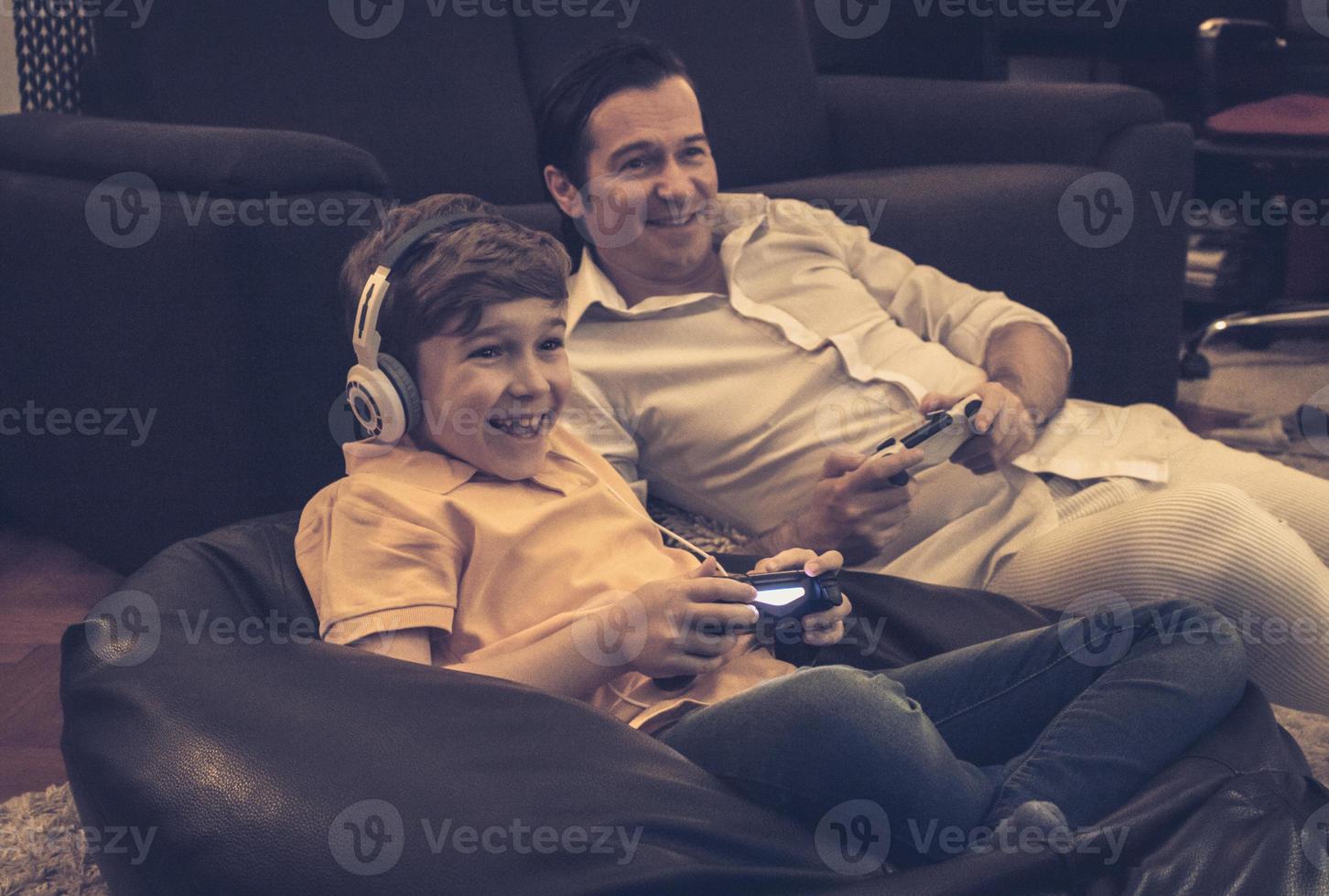 fröhlicher sohn und vater, die zu hause videospiele spielen. foto