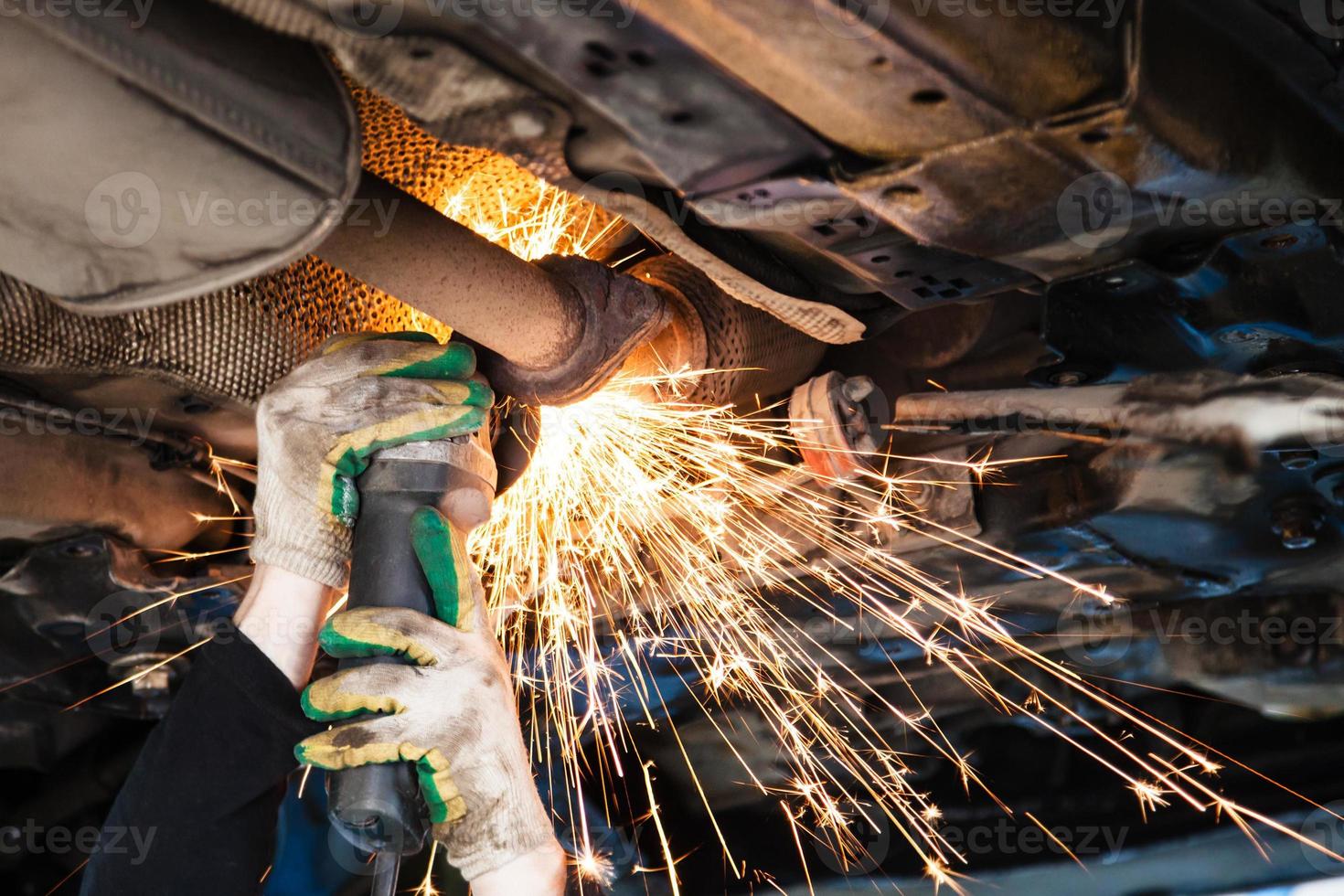 Reparaturwerkstatt schneidet alten Schalldämpfer am Auto mit Winkelschleifer foto