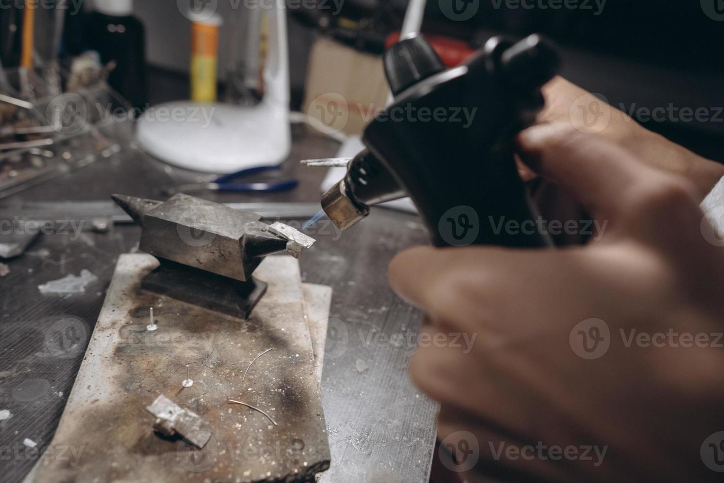 in der werkstatt lötet eine juwelierin schmuck foto