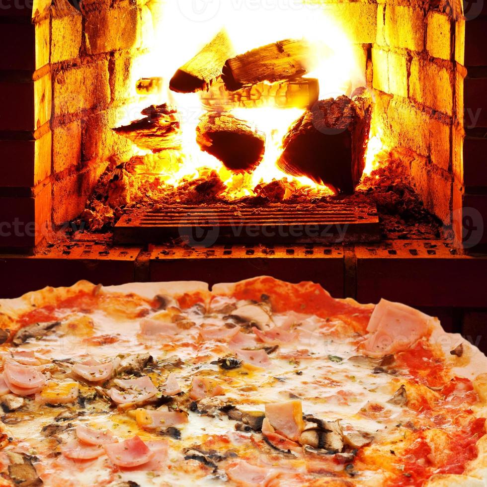 Pizza mit Schinken, Champignons und offenem Feuer im Ofen foto