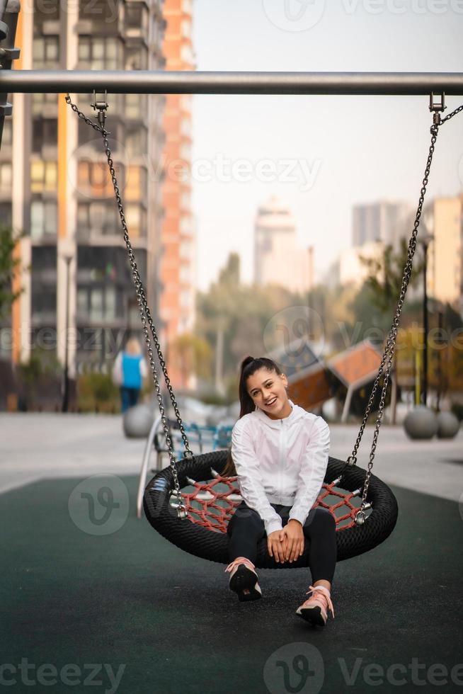 Junge Frau reitet auf einer Schaukel auf dem Spielplatz. foto