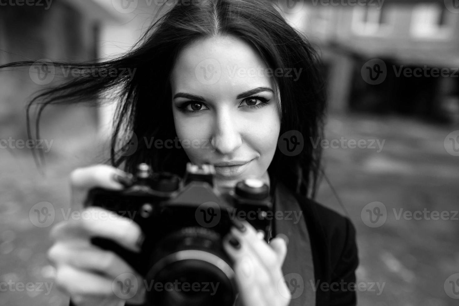 schöne Fotografin, die mit der Kamera posiert foto