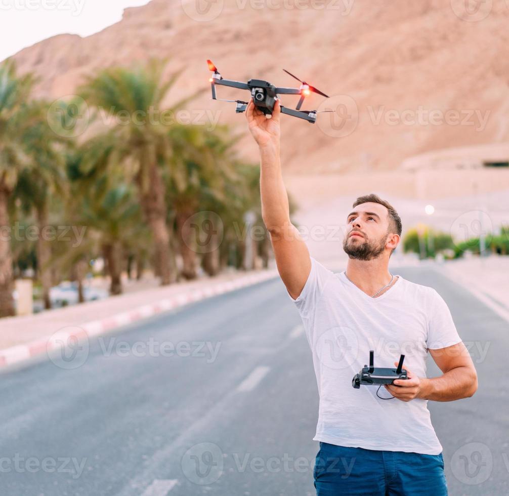 junger Mann, der Drohne vor dem Flug in die Natur hält foto