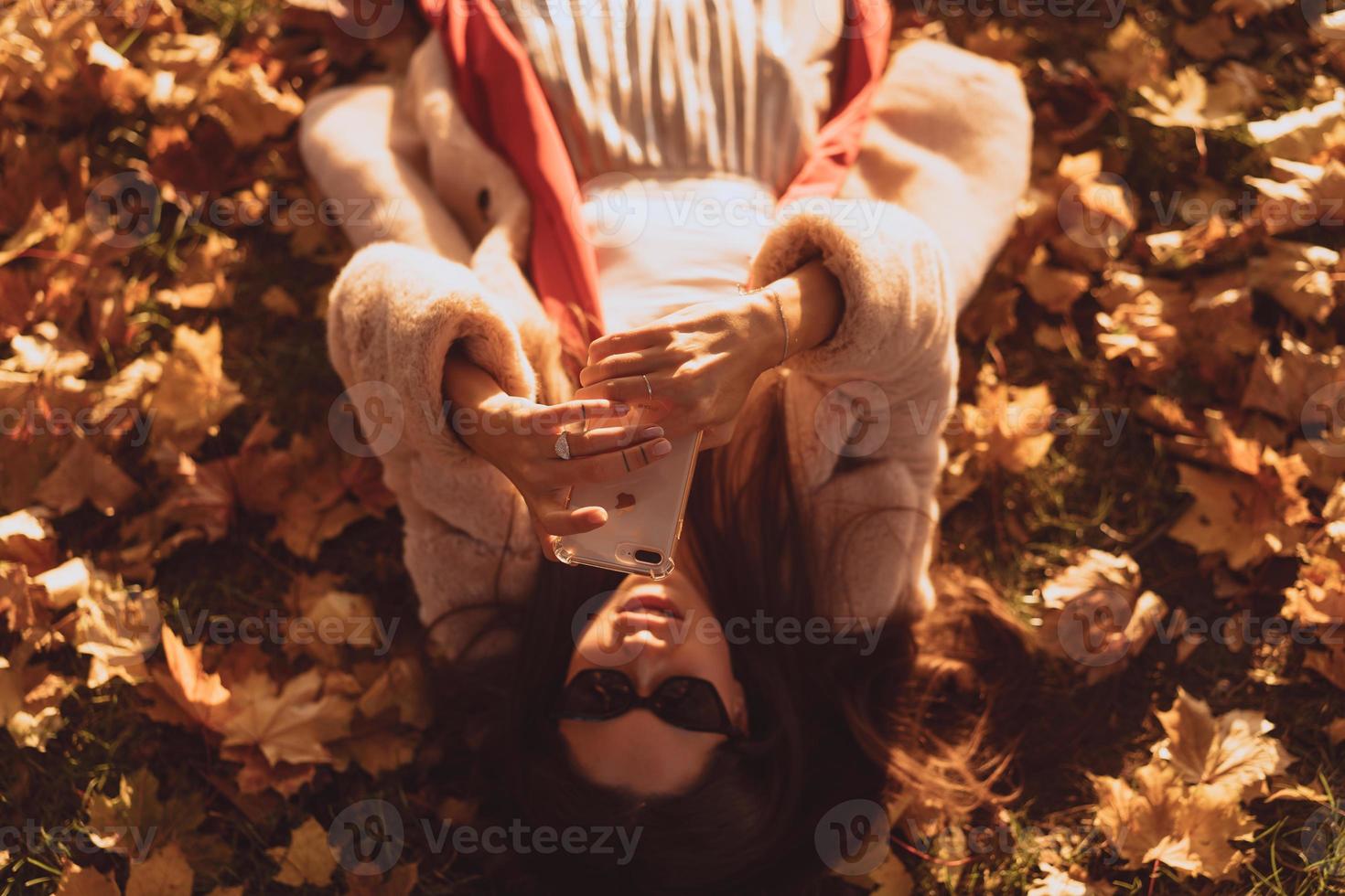 Draufsicht der schönen jungen Frau liegt auf Herbstlaub foto