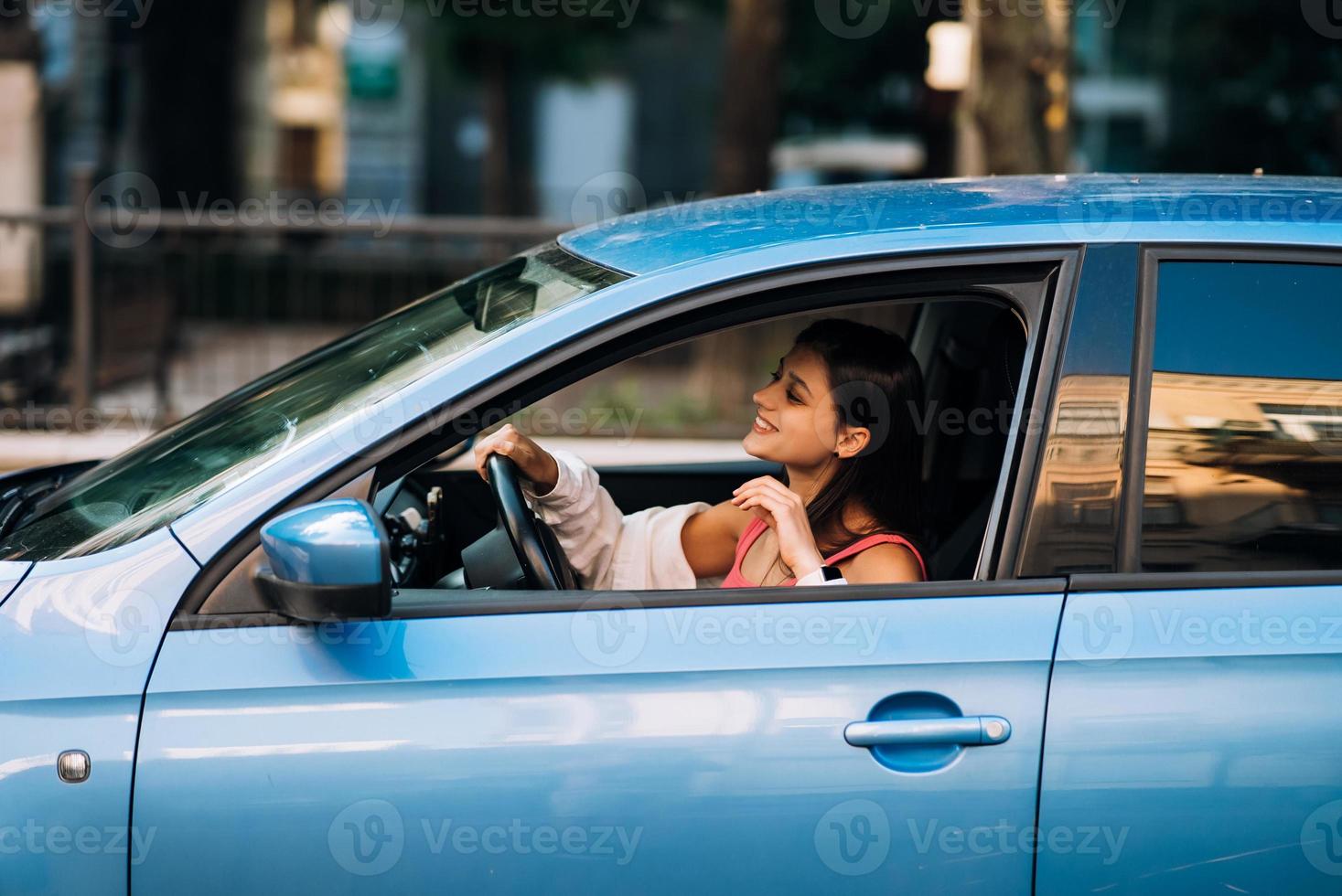 schöne lächelnde frau, die auto fährt, mädchen, das im auto sitzt foto