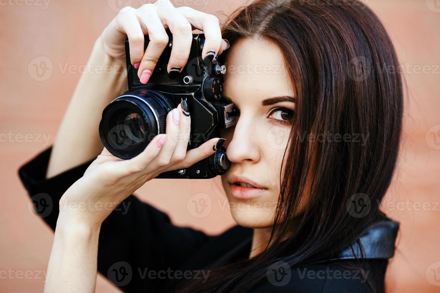 schöne Fotografin, die mit der Kamera posiert foto