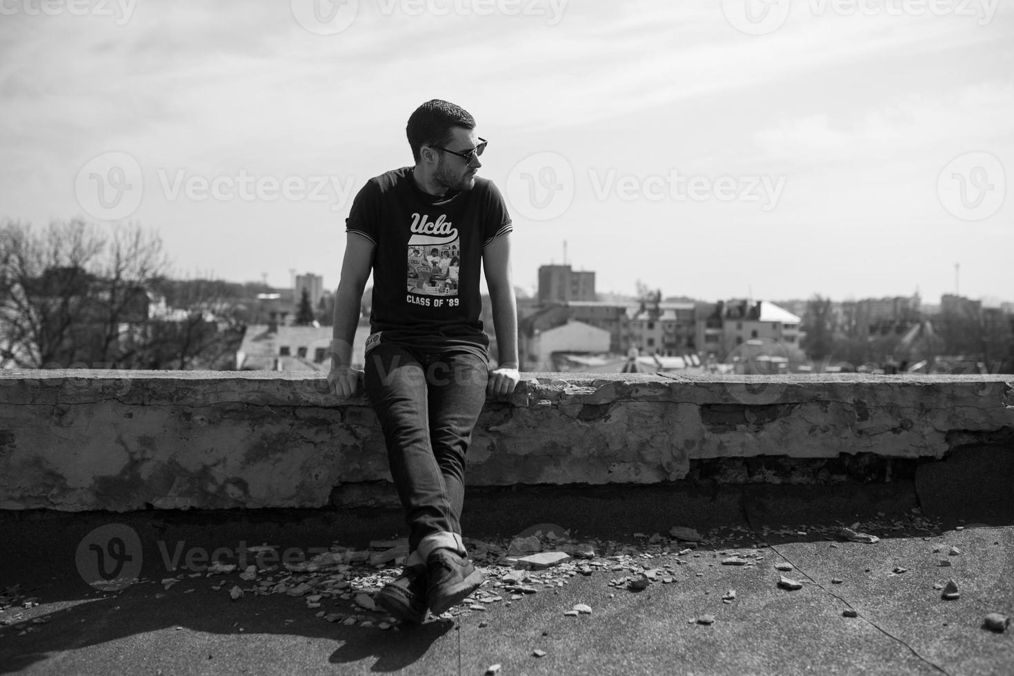 Der Mann in den authentischen Stiefeln und Jeanskanten auf dem Dach des Gebäudes in der Altstadt foto