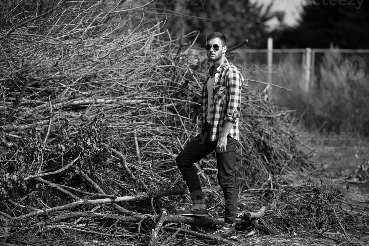 der Mann in den authentischen Stiefeln und Selvedge-Jeans auf dem Hintergrund von Ästen foto