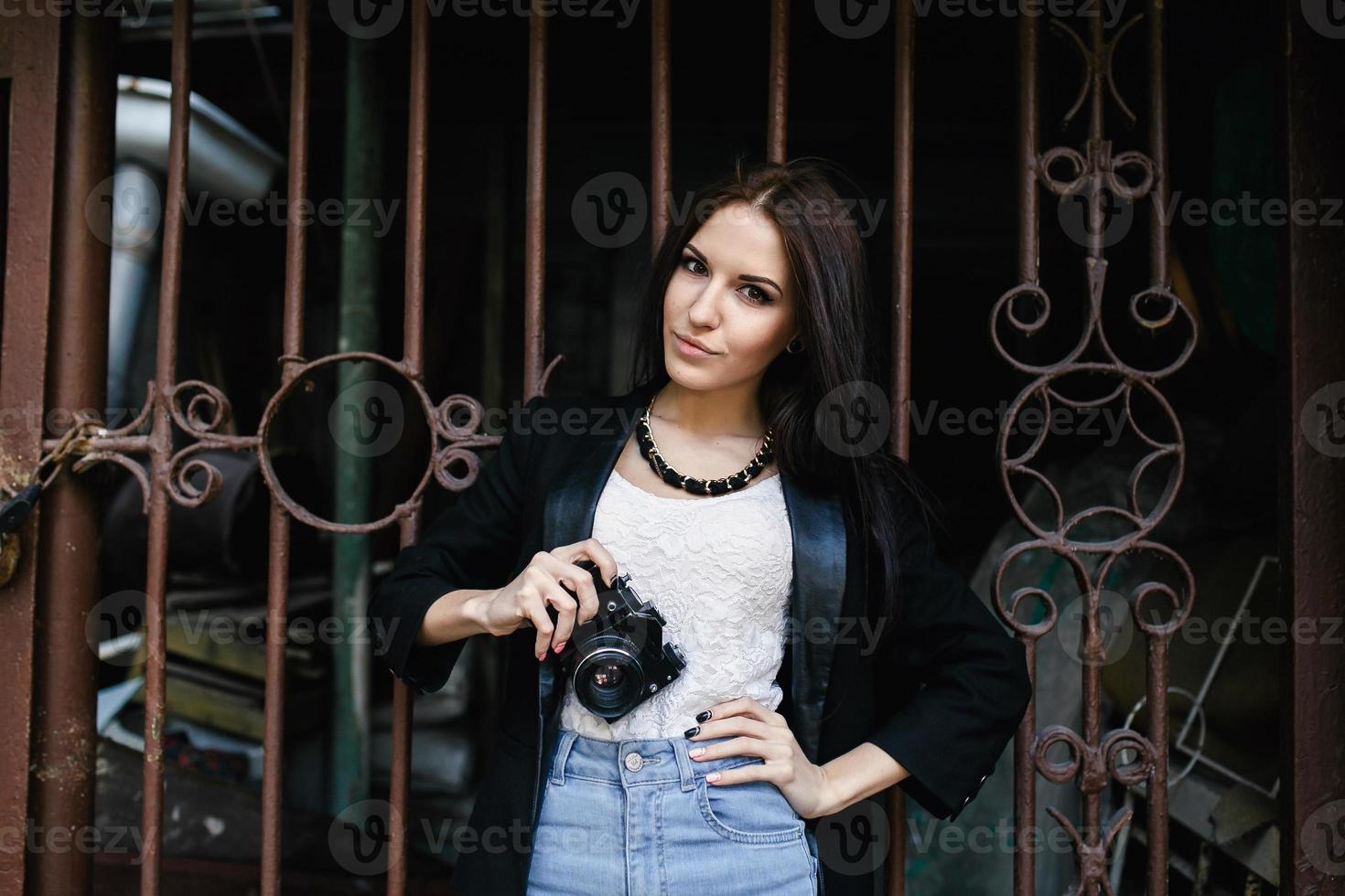 schönes Mädchen, das mit einer Kamera an einer Wand steht foto