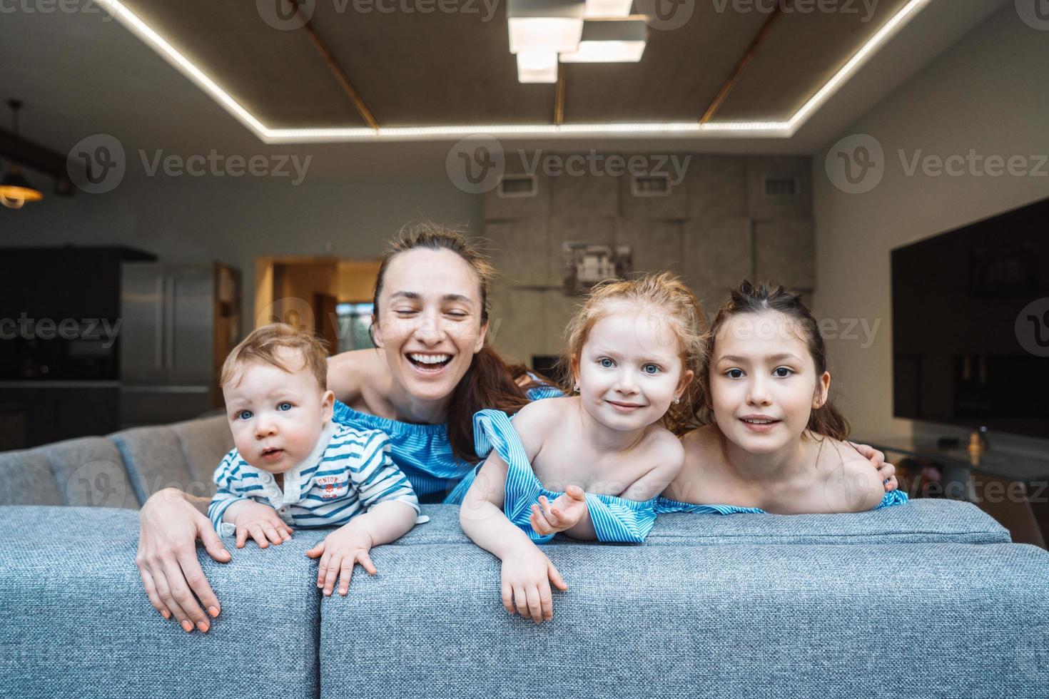 Mama, zwei Töchter und ein kleiner Sohn auf der Couch foto