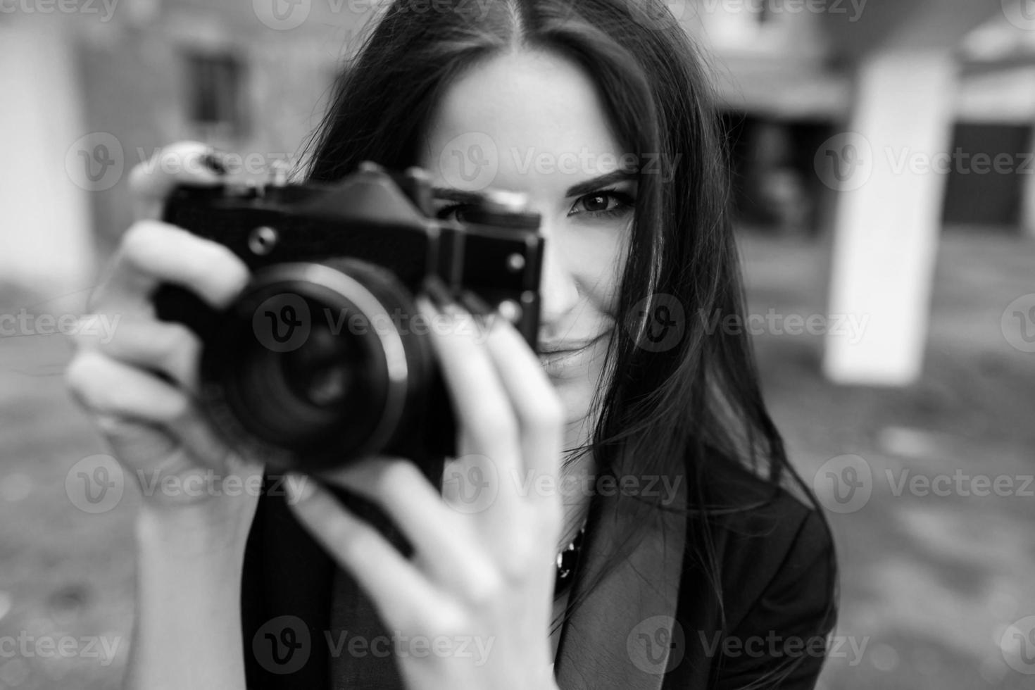 schöne Fotografin, die mit der Kamera posiert foto