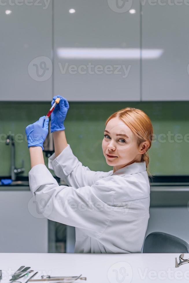 weiblicher medizinischer oder wissenschaftlicher Forscher, der ein Reagenzglas in einem Labor betrachtet. foto