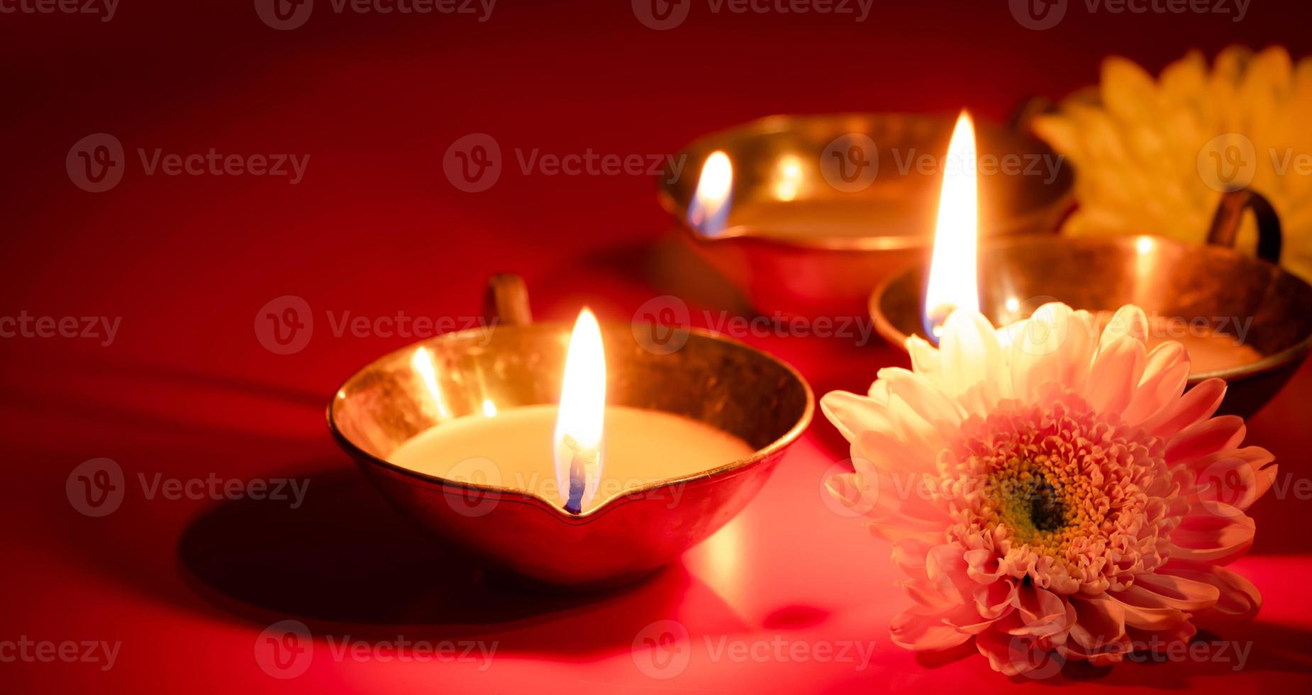 Frohes Diwali. Diya-Öllampe und Blumen auf rotem Hintergrund. traditionelle hinduistische feier. religiöser Feiertag des Lichts. foto