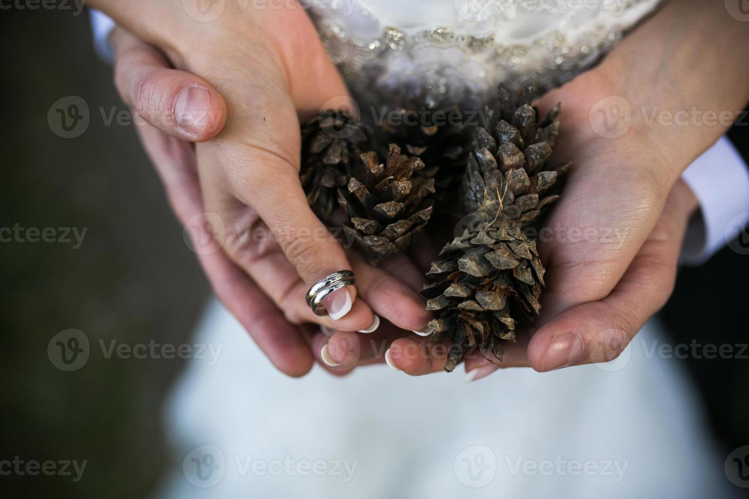 braut und bräutigam, die hochzeitsringe und herbstblätter in den händen halten foto