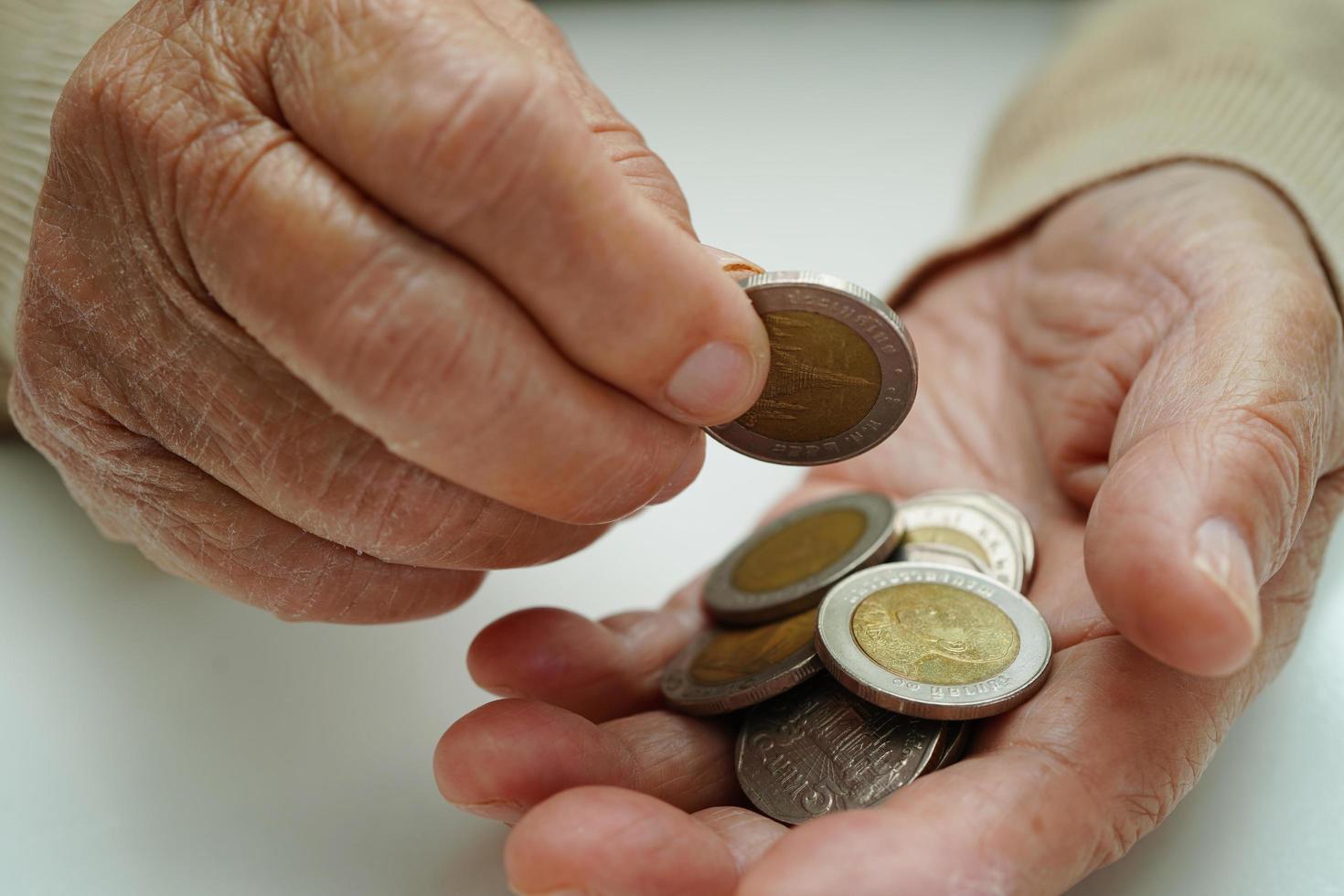 pensionierte ältere frau, die geldmünzen zählt und sich um monatliche ausgaben und die zahlung der behandlungsgebühr sorgt. foto