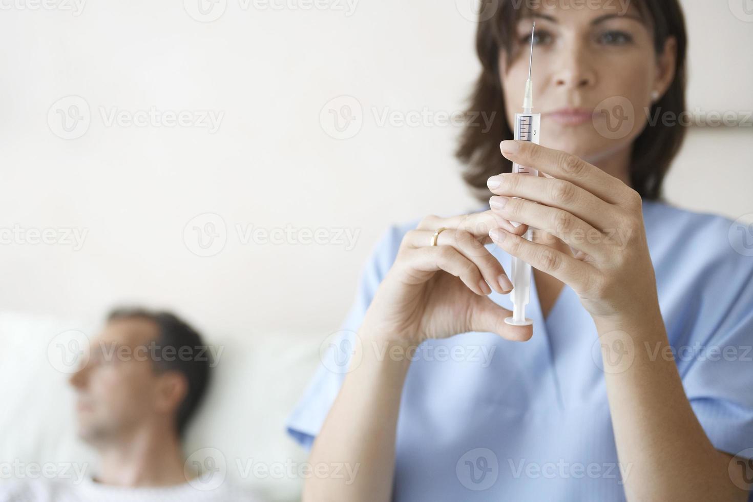 Krankenschwester bereitet Spritze für die Injektion durch den Patienten vor foto