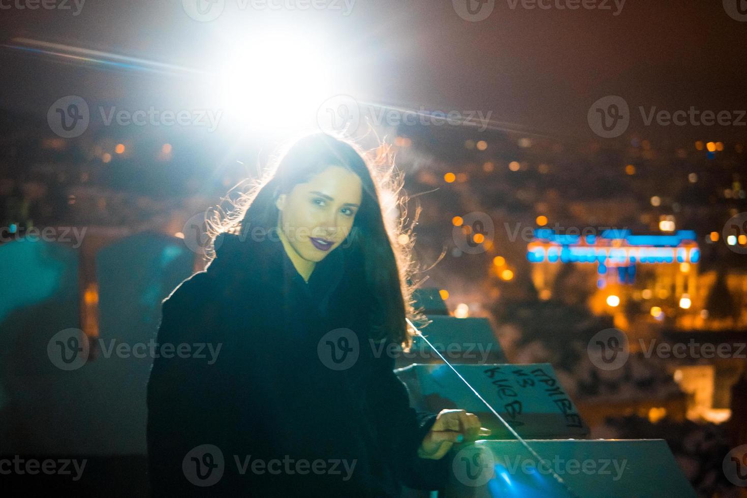 Frau auf dem Hintergrund des Stadtbildes bei Nacht foto
