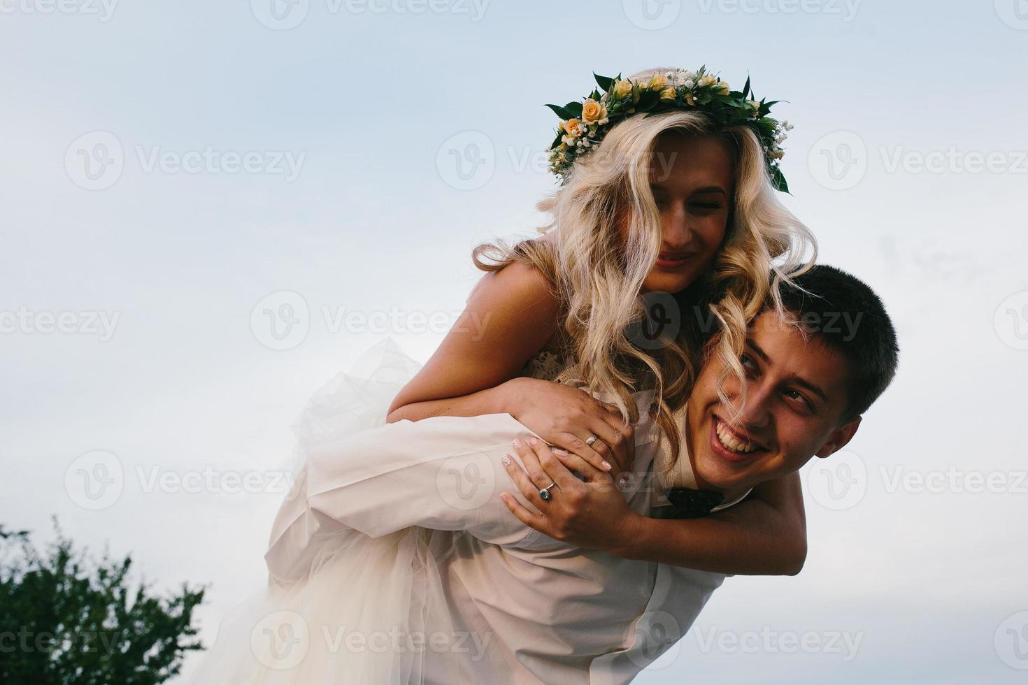 bräutigam trägt braut auf dem rücken im freien foto