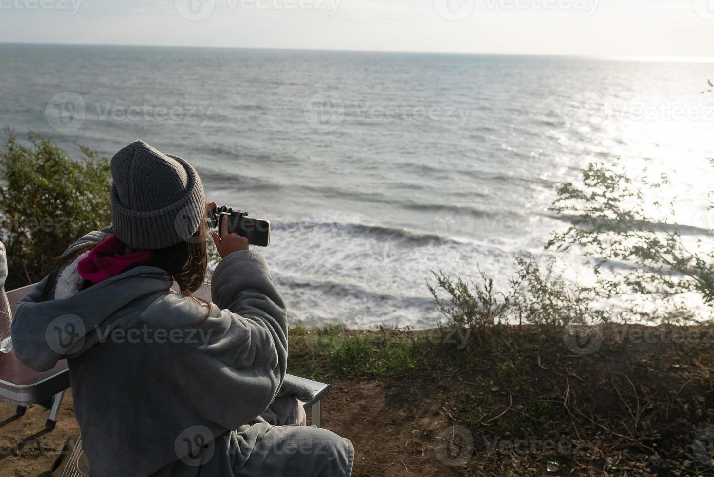 junge Frau macht ein Foto auf einem Smartphone der Meereslandschaft