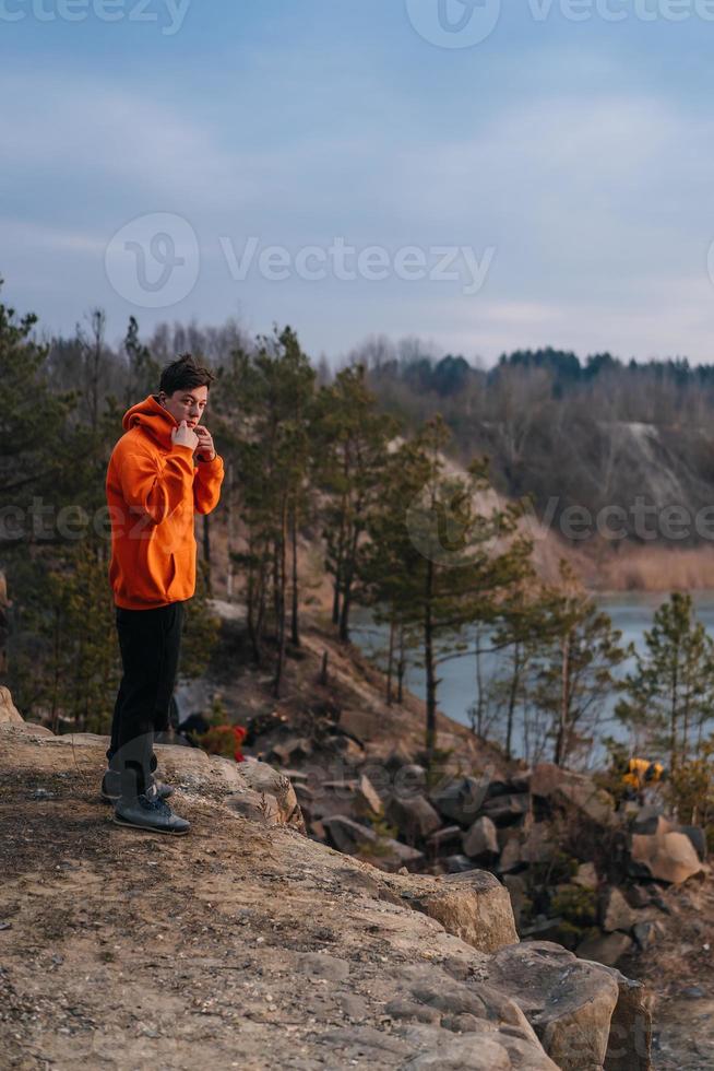 Ein junger Mann, der am Rand einer Klippe steht, posiert für die Kamera foto