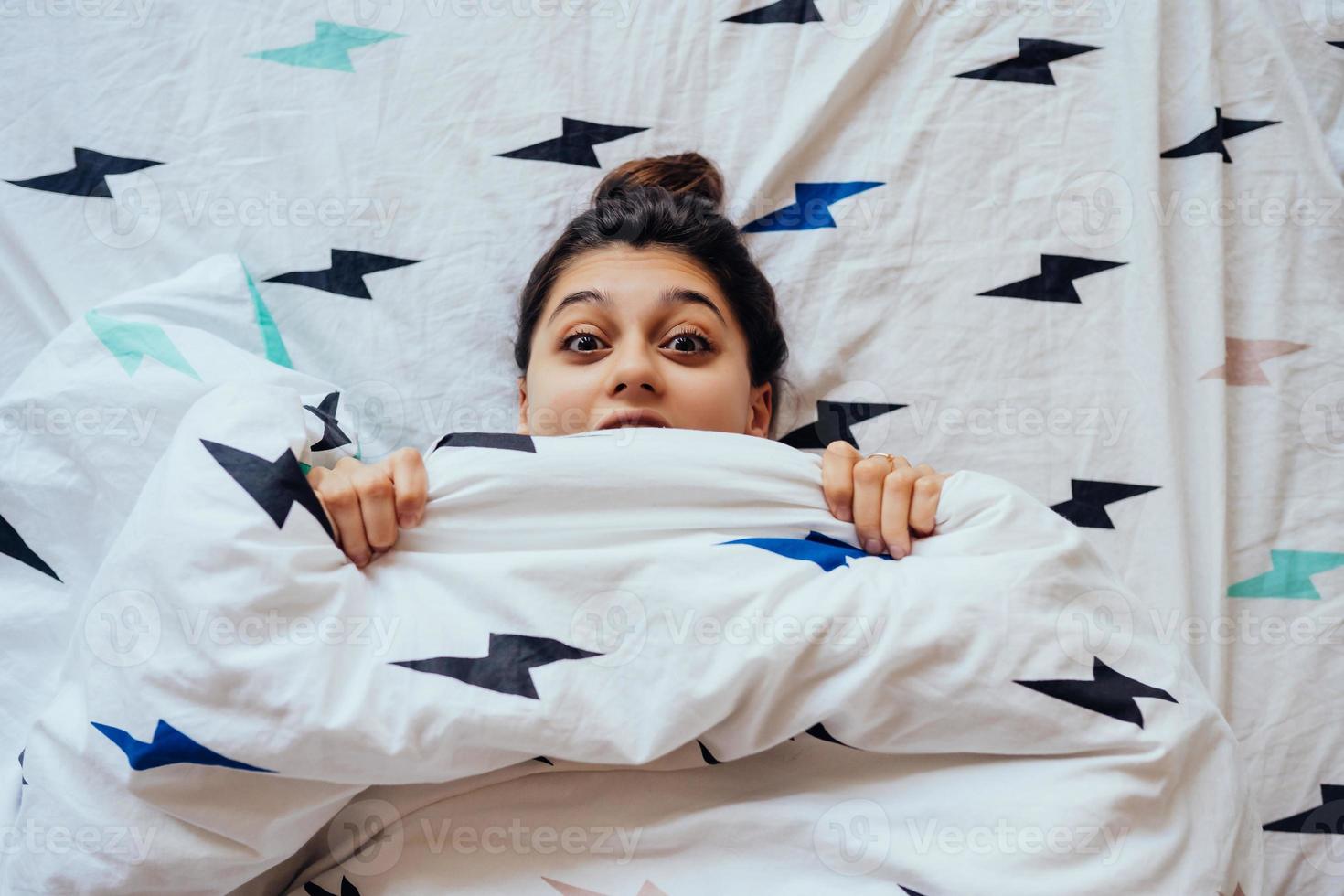 Nahaufnahme einer schönen jungen Frau liegt im Bett, das mit einer Decke bedeckt ist. foto