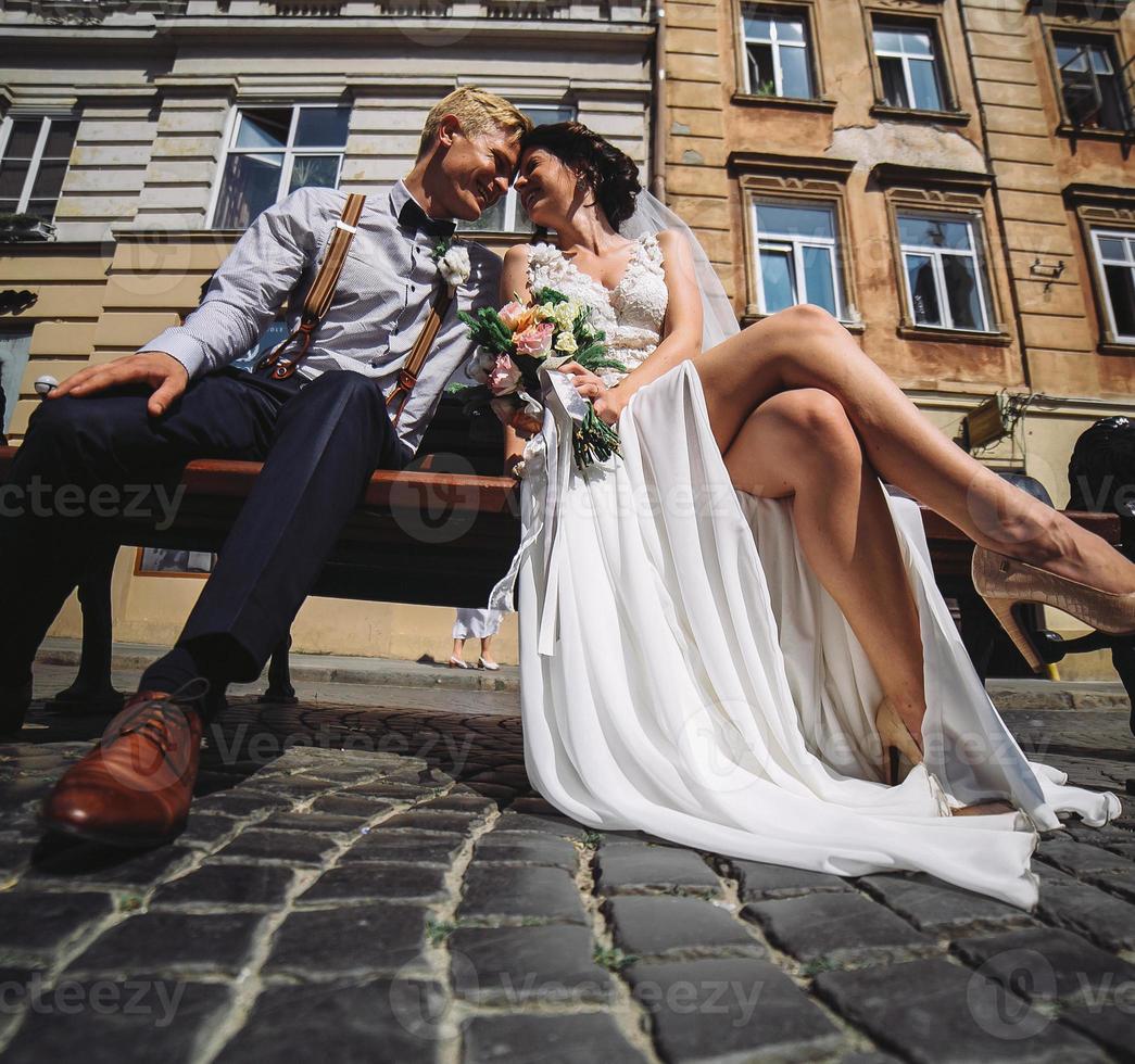 Braut und Bräutigam sitzen auf der Bank foto