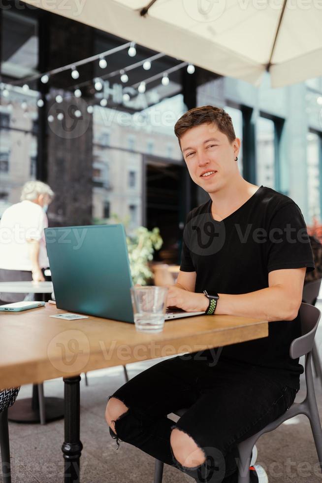 Porträt eines Mannes, der an einem Tisch sitzt und an einem Laptop arbeitet. foto