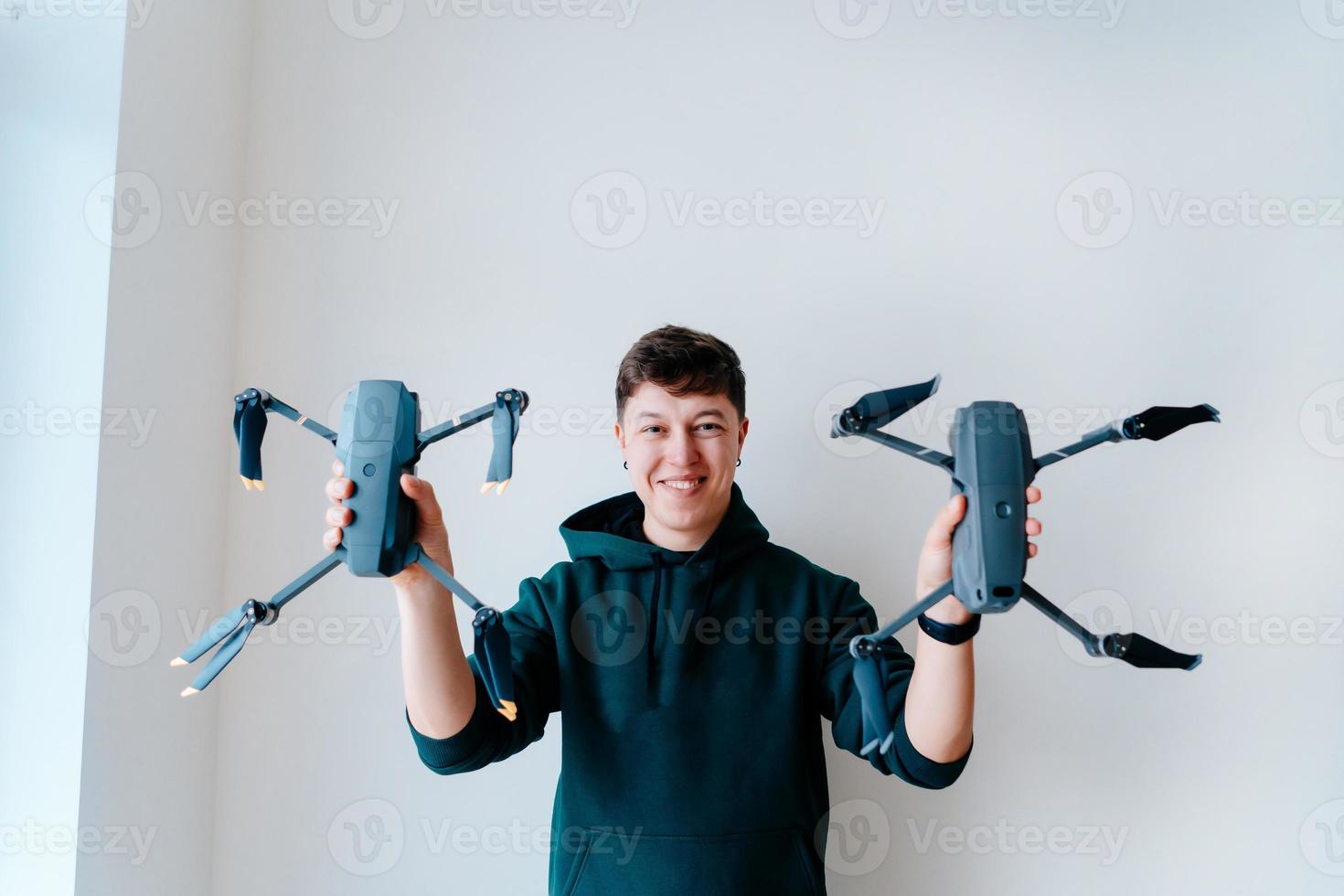 Typ hält zwei Quadrocopter gegen eine Wand foto