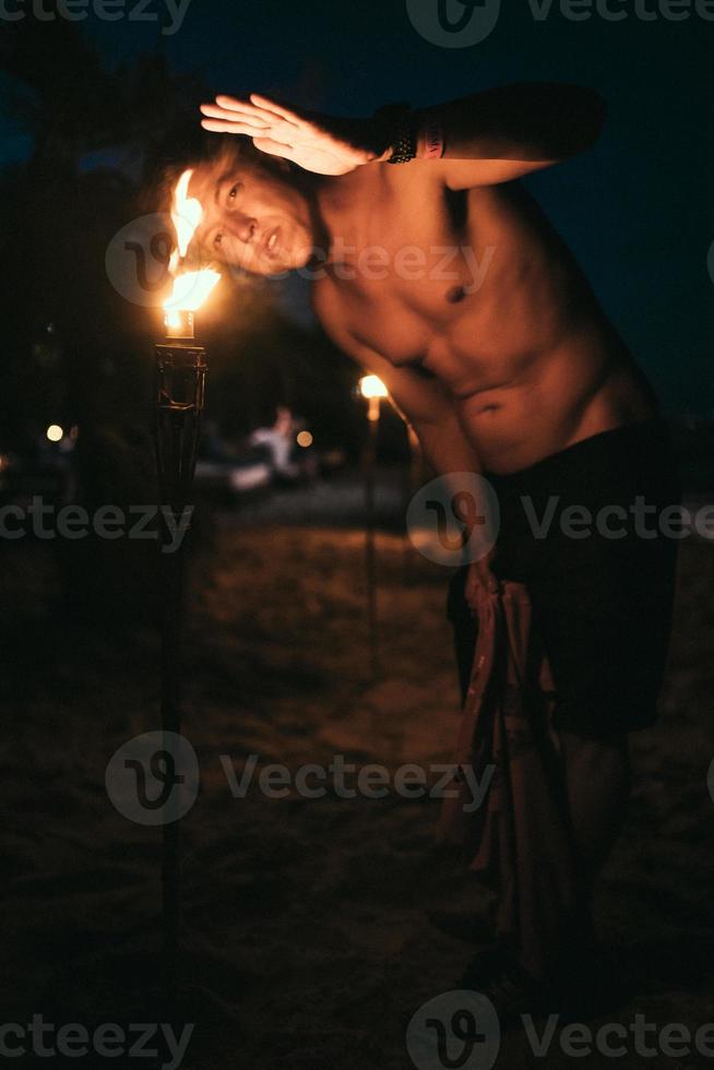 Typ mit Fackellicht nachts am Strand foto