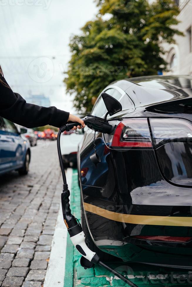 Frau in der Nähe von Elektroautos. Fahrzeug an der Ladestation aufgeladen. foto