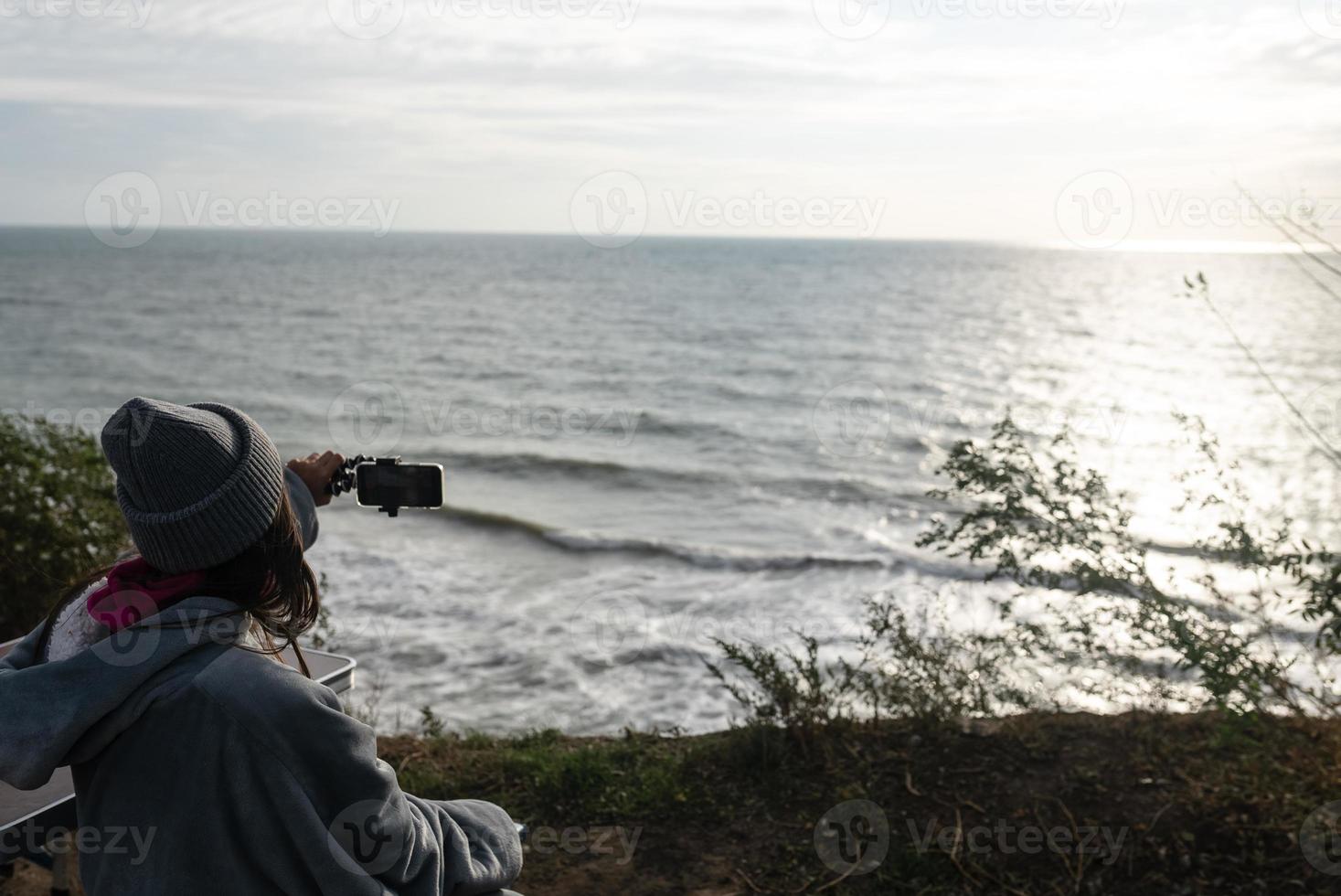 junge Frau macht ein Foto auf einem Smartphone der Meereslandschaft