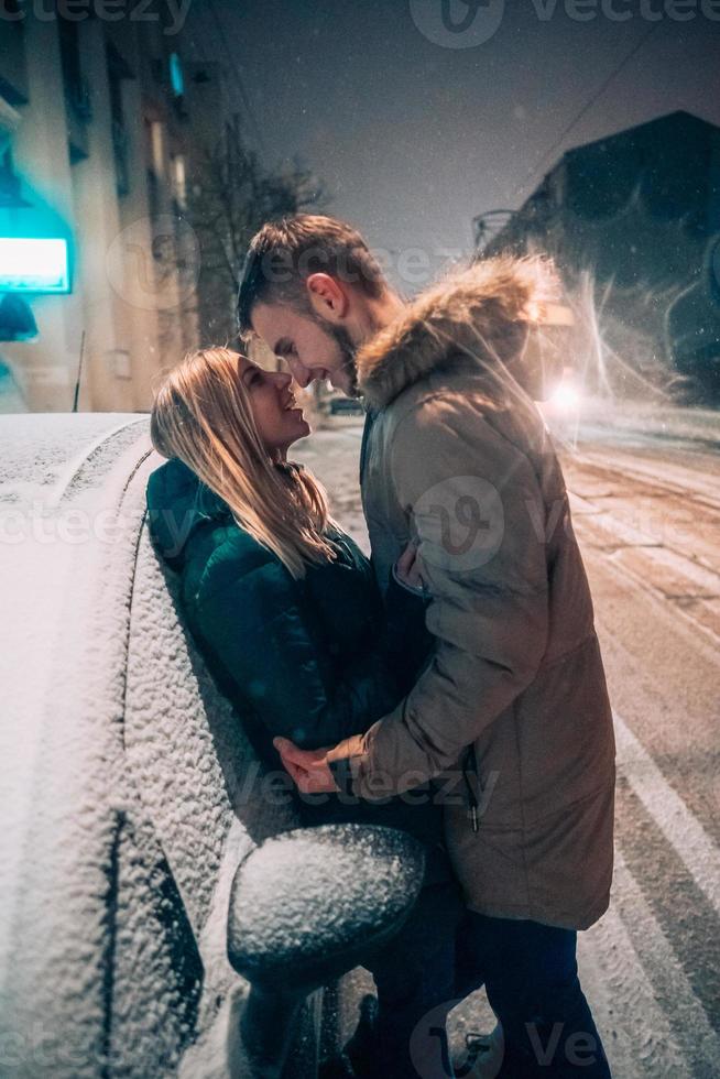 junges erwachsenes paar, das sich auf schneebedeckter straße küsst foto