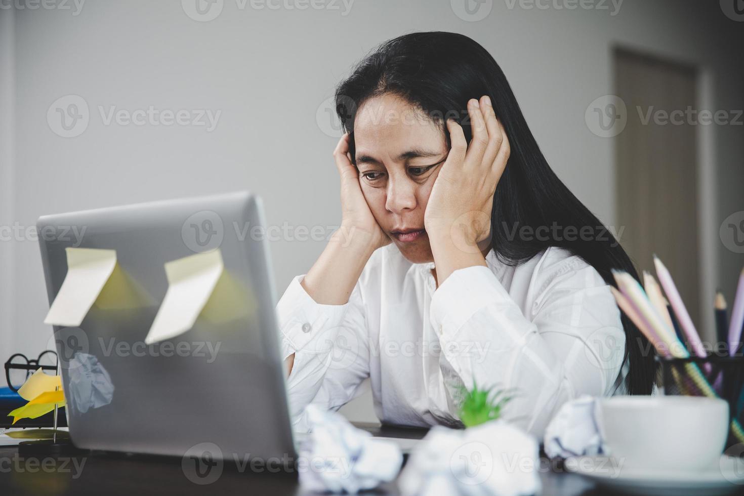 stress geschäftsfrau person von harter arbeit, depression im büro. müde und ängstliche mitarbeiterin mit unzufriedenem problemjob. junge Geschäftsfrau, die traurig vor Laptop-Computer auf Schreibtisch sitzt. foto