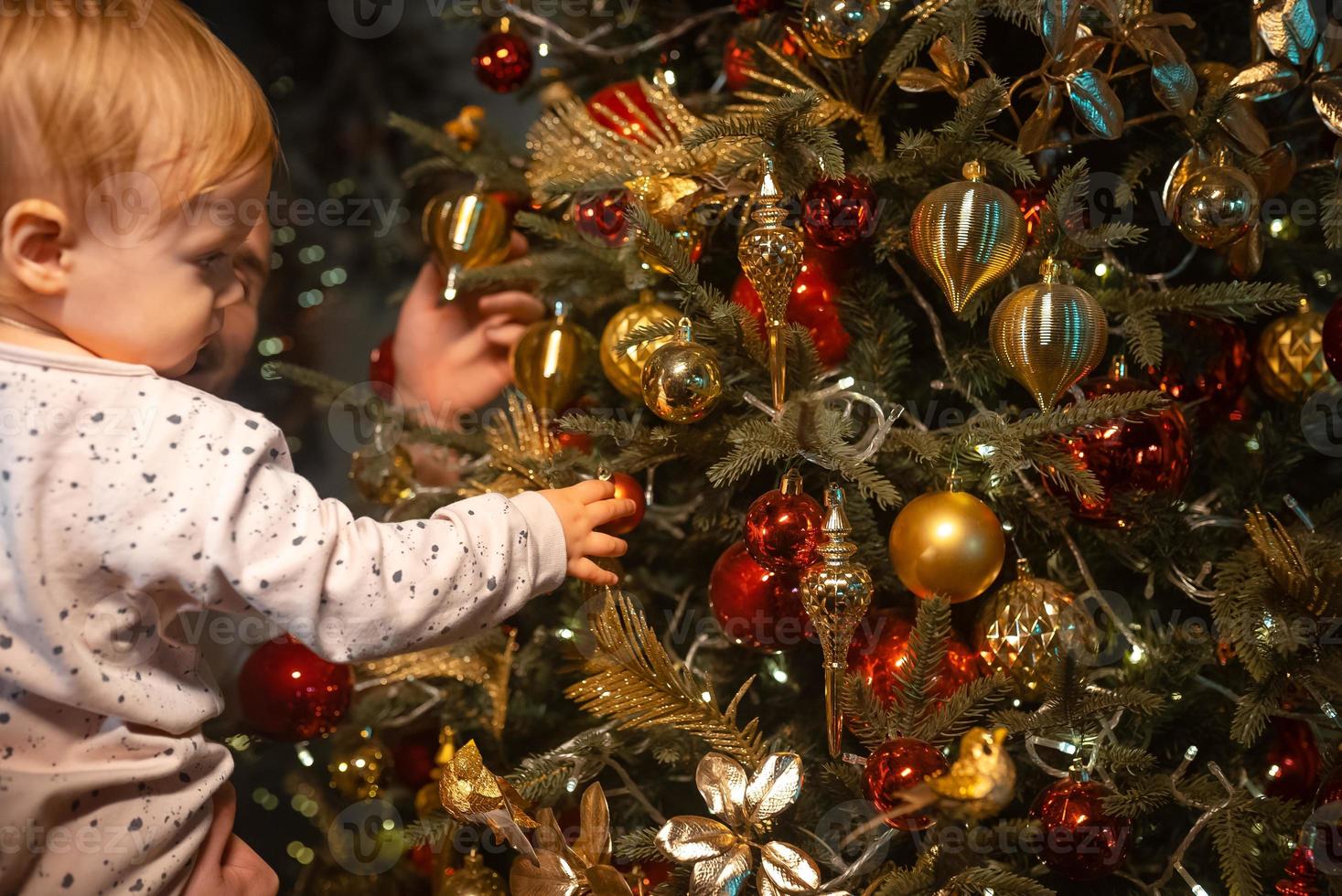 kleiner Junge spielt am Weihnachtsbaum foto