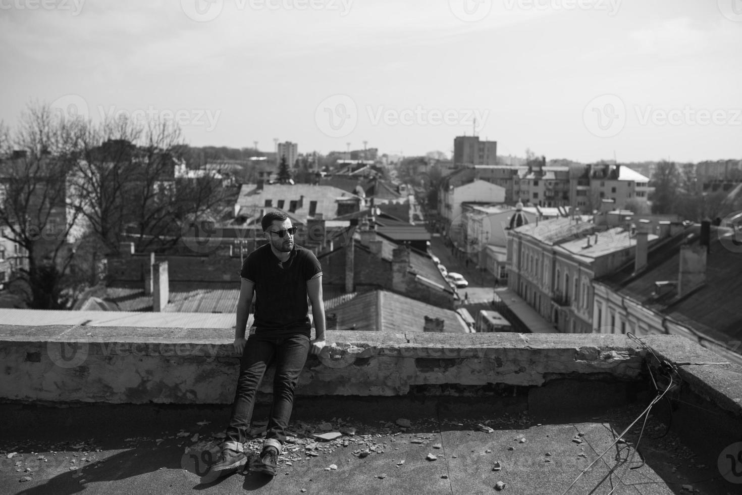 Der Mann in den authentischen Stiefeln und Jeanskanten auf dem Dach des Gebäudes in der Altstadt foto