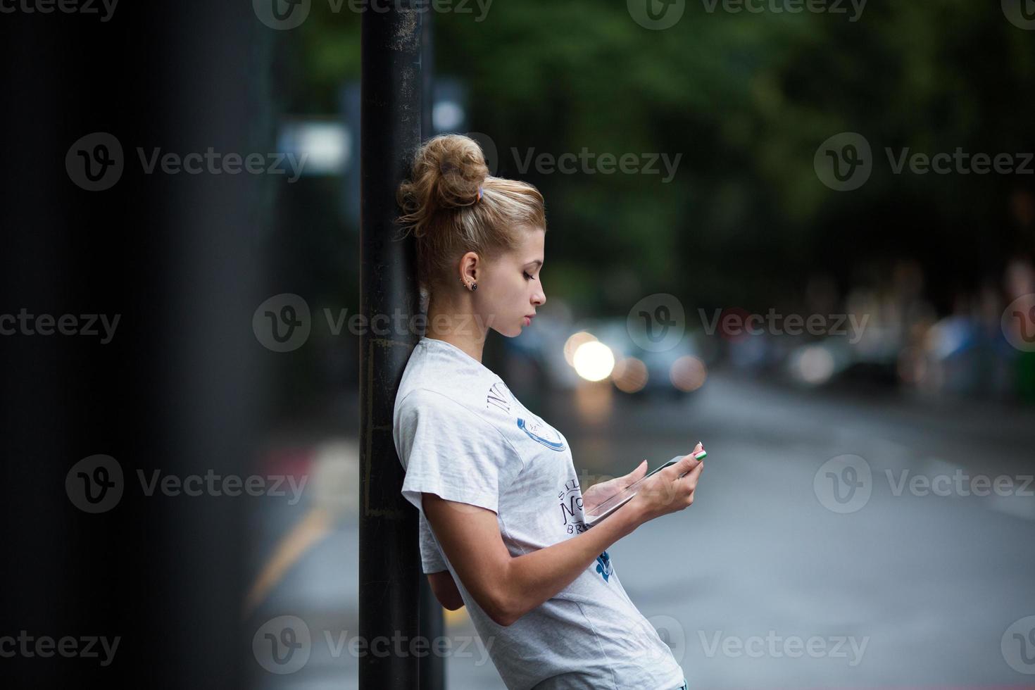 süße Mädchen mit Tablet an einer Bushaltestelle foto