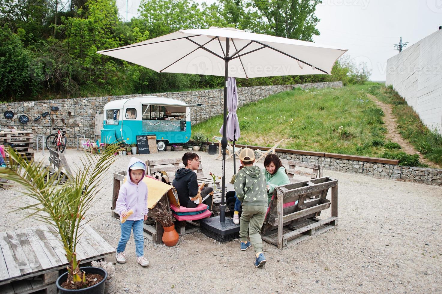 Familie sitzt im Café mit gemütlichem kleinen Minibus-Lebensmittelmarkt. foto