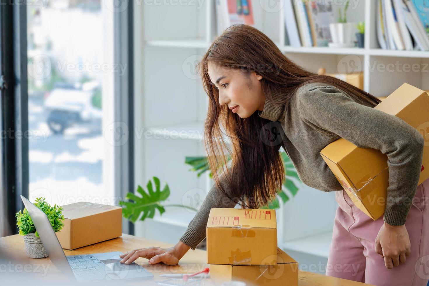 Von zuhause aus arbeiten. glückliche frauen, die produkte online verkaufen, gründen einen kleinunternehmer, indem sie mit einem laptop die preise berechnen und sich auf den versand vorbereiten. foto