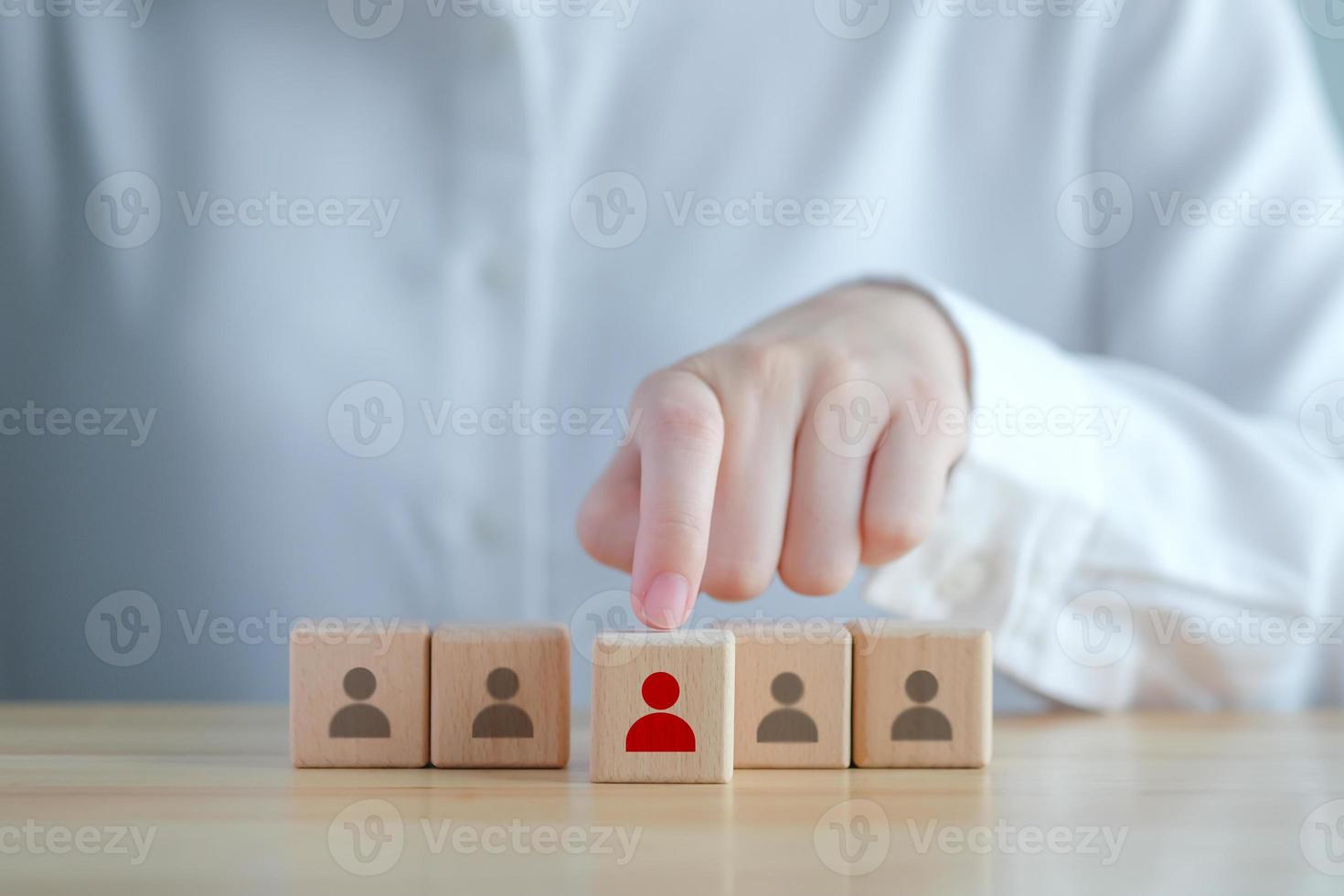 Einstellung von Unternehmen und Personalauswahl. Karrieremöglichkeiten. Personalmanagement. hand, die rotes menschliches symbol auf holzblock wählt. Wahl des Mitarbeiterführers oder des neuen Mitarbeiters aus der Menge. foto