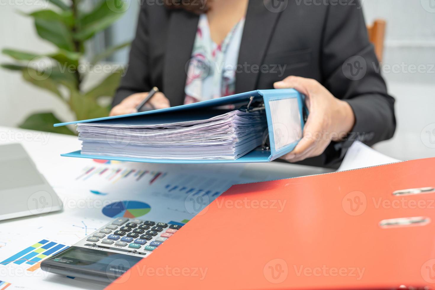 asiatischer buchhalter, der mappe hält und arbeitet, die finanzprojektbuchhaltung mit diagrammdiagramm und laptop im modernen büro-, finanz- und geschäftskonzept analysiert. foto